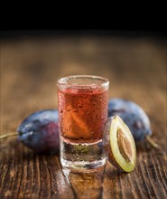 Plum Liqueur on rustic wooden background as close-up shot