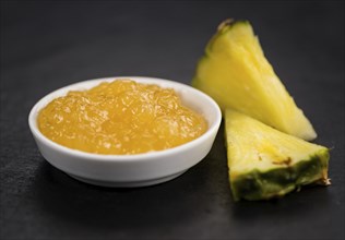 Portion of Pineapple Jam as detailed close up shot on a slate slab, selective focus