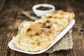 Wooden table with fresh homemade Empanadas (detailed close-up shot, selective focus)