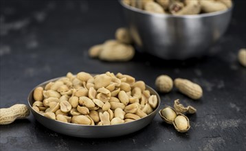 Roasted and salted Peanuts on vintage background (close-up shot, selective focus)