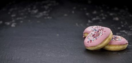 Portion of pink glazed Donuts (detailed close-up shot)