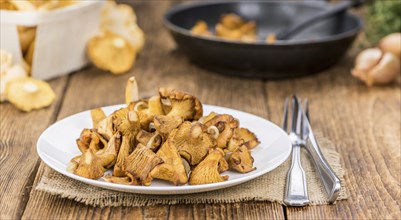 Fried Chanterelles on rustic wooden background as close-up shot