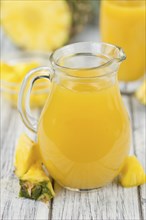 Pineapple Juice as high detailed close-up shot on a vintage wooden table, selective focus