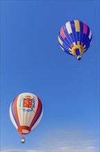 Two colorful hot air balloons with striped patterns floating in a clear blue sky, Belarus, Minsk,