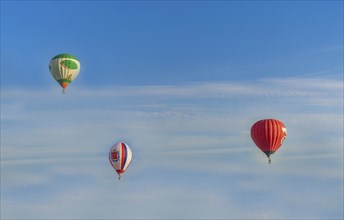 Hot air balloons in different colors soaring through a blue sky with light clouds, Belarus, Minsk,