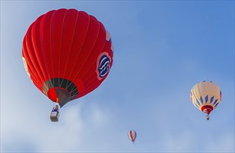 Hot air balloons of red and white colors float against a clear blue sky, Belarus, Minsk, Europe