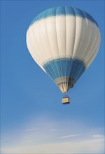 A hot air balloon with a blue and white pattern floats peacefully in a clear blue sky, Belarus,