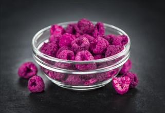 Portion of Dried Raspberries as detailed close up shot on a slate slab, selective focus