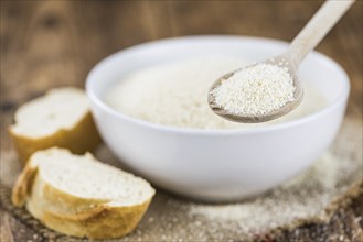 Wooden spoon with Breadcrumbs (close-up shot, selective focus) on an old wooden table