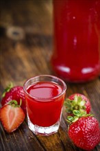 Fresh made Strawberry liqueur on an old and rustic wooden table, selective focus, close-up shot