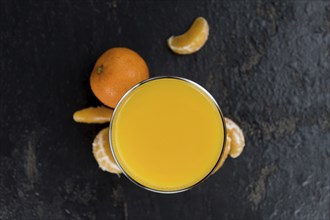 Homemade Tangerine Juice (close-up shot, selective focus) on a rustic background