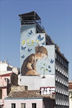 Child among butterflies looking at small plant, symbol of nature, mural at Play Hotel by street