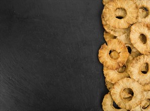 Portion of Dried Pineapple Rings on a rustic slate slab, selective focus, close-up shot