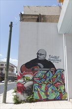 Graffiti with portrait of the Greek musician Giorgos Moukidis, holding a guitar, Präus Street,