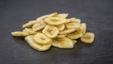 Portion of Dried Banana Chips on a rustic slate slab, selective focus, close-up shot