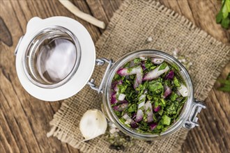 Healthy homemade Chimichurri on a wooden table as detailed close-up shot (selective focus)