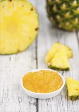 Pineapple Jam as high detailed close-up shot on a vintage wooden table, selective focus