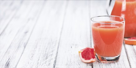 Some freshly squeezed Grapefruit Juice on a vintage background (close-up shot, selective focus)