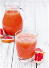 Vintage wooden table with a portion of freshly squeezed Grapefruit Juice (selective focus)