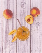 Peach Jam on an old wooden table as detailed close-up shot, selective focus