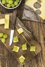 Vintage wooden table with Cheese blocks and grapes as detailed close-up shot (partyfood)