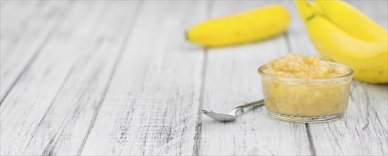 Banana Puree on wooden background (selective focus, close-up shot)