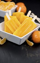 Portion of fresh homemade Tangerine Popsicles (close-up shot, selective focus) on a vintage