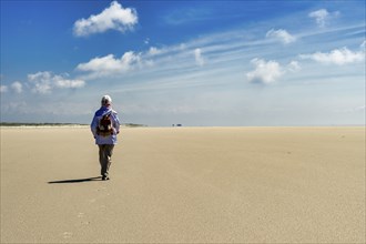 Lonely elderly woman walking on the beach, endless expanse, North Sea, St. Peter Ording, Schleswig