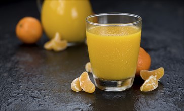 Portion of fresh made Tangerine Juice (close-up shot, selective focus)