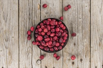 Healthy Cranberries (dried) on a wooden table as detailed close-up shot (selective focus)