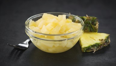 Portion of Chopped Pineapple (preserved) on a rustic slate slab, selective focus, close-up shot