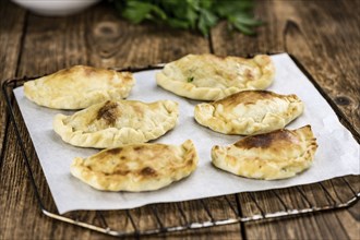 Wooden table with fresh homemade Empanadas (detailed close-up shot, selective focus)