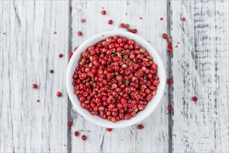 Pink Peppercorns on an old wooden table as detailed close-up shot, selective focus