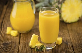 Pineapple Juice as high detailed close-up shot on a vintage wooden table, selective focus