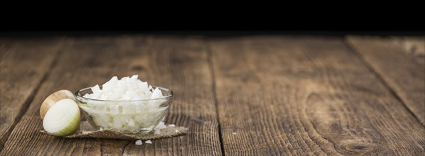 Chopped white onions on an old wooden table as detailed close-up shot, selective focus