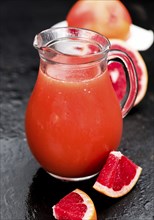 Some freshly squeezed Grapefruit Juice on a vintage background (close-up shot, selective focus)