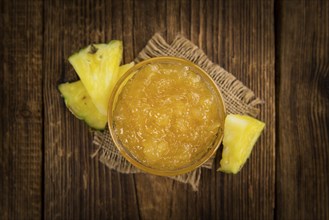 Pineapple Jam as high detailed close-up shot on a vintage wooden table, selective focus