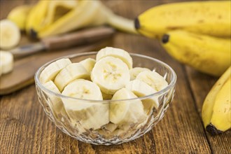 Sliced Bananas as high detailed close-up shot on a vintage wooden table, selective focus