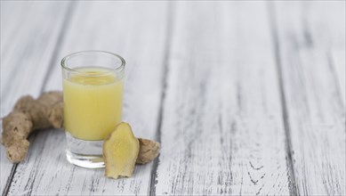 Healthy Ginger Sap on a wooden table as detailed close-up shot (selective focus)