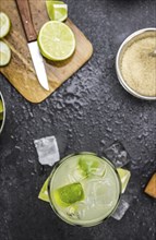 Caipirinha made with fresh limes, ice and sugar as close-up shot