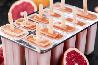 Vintage slate slab with some freshly made Grapefruit Popsicles (selective focus, close-up shot)