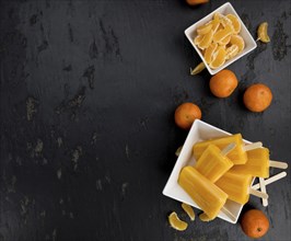 Slate slab with homemade Tangerine Popsicles (selective focus) as detailed close-up shot