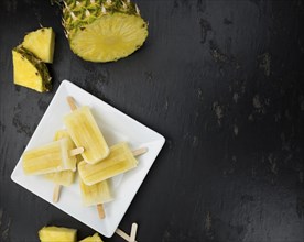 Some homemade Pineapple Popsicles (selective focus) on a rustic background