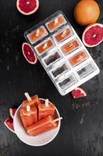 Some freshly made Grapefruit Popsicles (with some fresh fruits, selective focus)