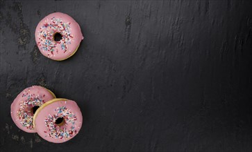 Portion of pink glazed Donuts (detailed close-up shot)