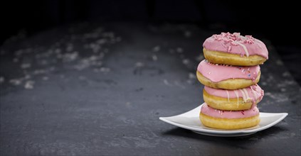 Portion of pink glazed Donuts (detailed close-up shot)