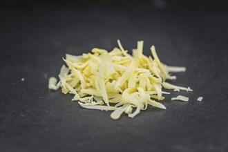 Homemade Grated Cheese (close-up shot) on a vintage slate slab