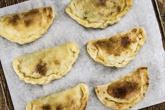 Wooden table with fresh homemade Empanadas (detailed close-up shot, selective focus)