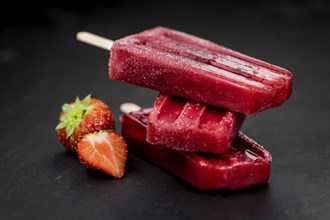 Homemade Strawberry Popsicles (close-up shot, selective focus) on vintage background