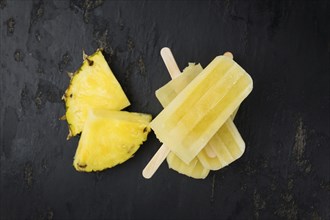 Some homemade Pineapple Popsicles (selective focus) on a rustic background